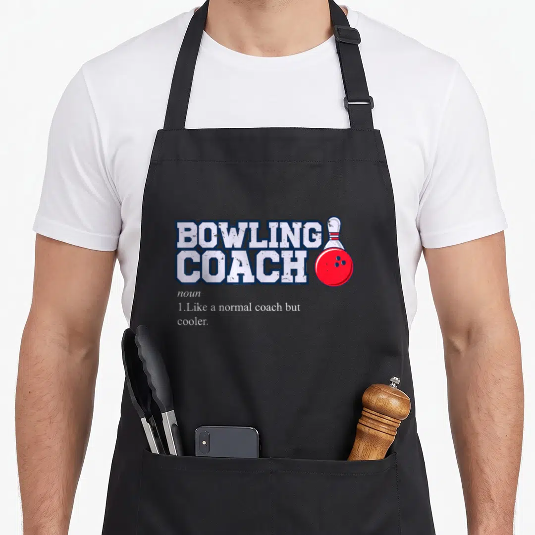 Bowling bowl apron - BOWLING COACH text with red bowling ball and white pin graphic — shown on a black cotton canvas apron against a white background