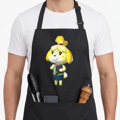 Isabelle animal apron - Cartoon yellow dog character holding a black clipboard and pen wearing a green vest — shown on a black cotton canvas apron against a white background