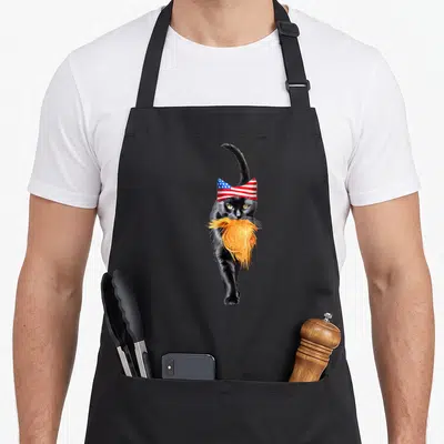 Childless cat lady apron - Realistic black cat walking with orange beard and American flag bowtie — shown on a black cotton canvas apron against a white background