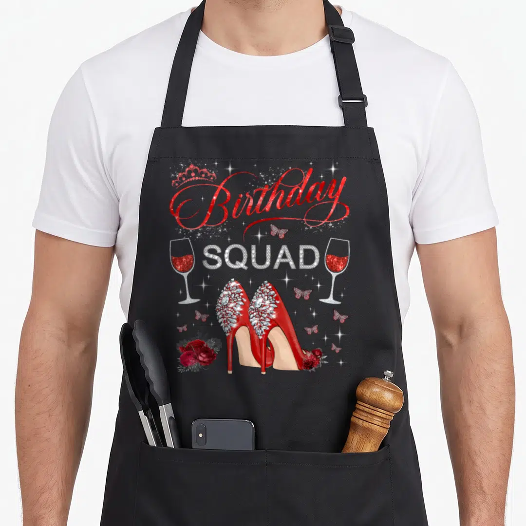 Squad butterfly apron - Red high heels with crown and birthday squad text between wine glasses — shown on a black cotton canvas apron against a white background