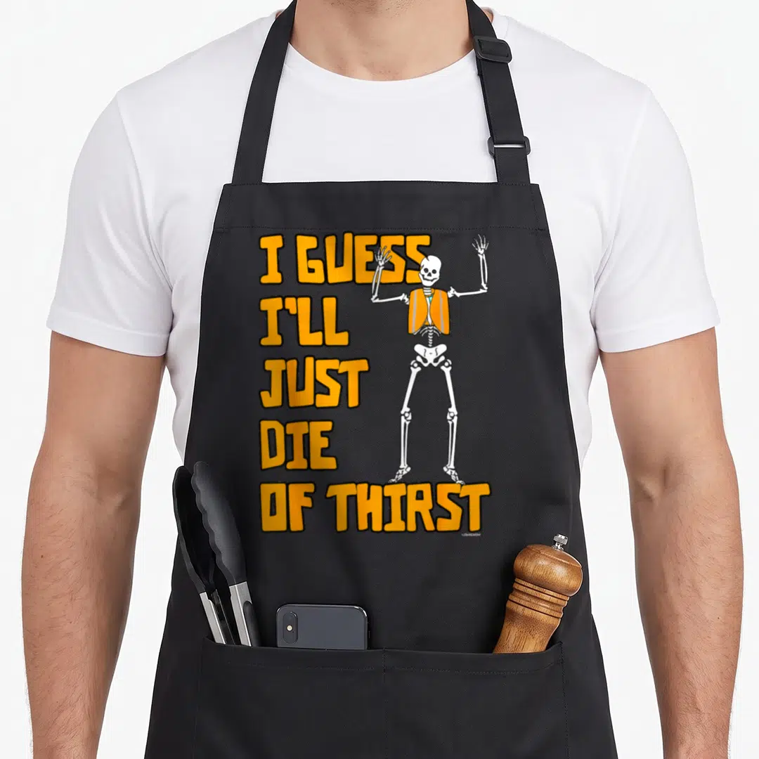 Guess tots apron - Cartoon skeleton in orange vest next to stacked orange text reading I guess I'll just die of thirst — shown on a black cotton canvas apron against a white background