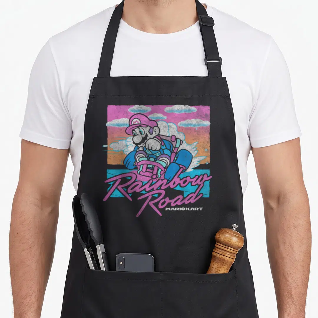 Pastel road apron - Mario in kart with pink Rainbow Road script and MARIOKART text against pastel clouds — shown on a black cotton canvas apron against a white background