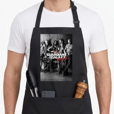 Shot galaxies apron - Grayscale group of five characters with Marvel Studios text and red Vol 2 logo — shown on a black cotton canvas apron against a white background
