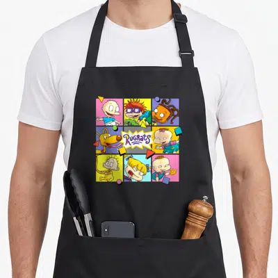 Tommy best friend aprons - Nine square panels of cartoon babies and a dog with a central Rugrats logo — shown on a black cotton canvas apron against a white background