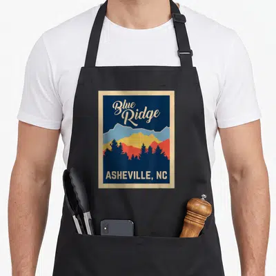 Blue asheville apron - Retro Blue Ridge mountains graphic with text Blue Ridge ASHEVILLE NC in blue and cream colors — shown on a black cotton canvas apron against a white background