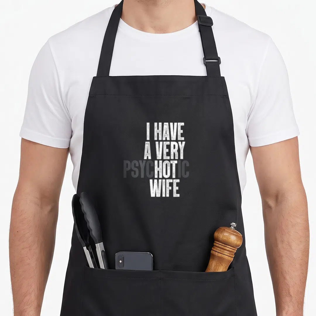Psychotic husband apron - Stacked white and grey text reading I HAVE A VERY PSYCHOTIC WIFE on grey background — shown on a black cotton canvas apron against a white background