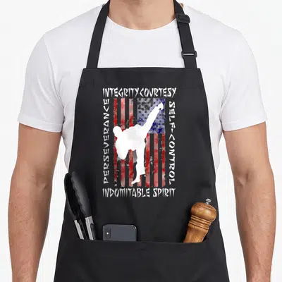 Tkd martial apron - Martial artist kicking over distressed flag surrounded by Integrity, Courtesy, Perseverance — shown on a black cotton canvas apron against a white background