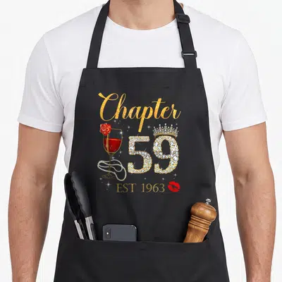 Chapter birthday apron - Gold Chapter text, rhinestone 59 with crown, red wine glass with rose and pearls, EST 1963 — shown on a black cotton canvas apron against a white background
