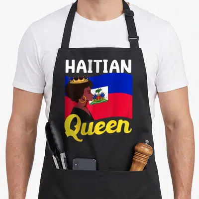 Haiti queen apron - Woman profile with crown over waving blue red flag with HAITIAN Queen text — shown on a black cotton canvas apron against a white background