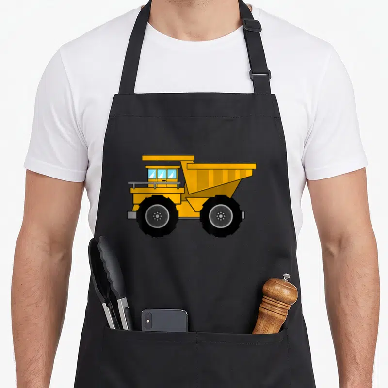 Cute dump truck apron - Yellow cartoon dump truck with black tires and grey background — shown on a black cotton canvas apron against a white background