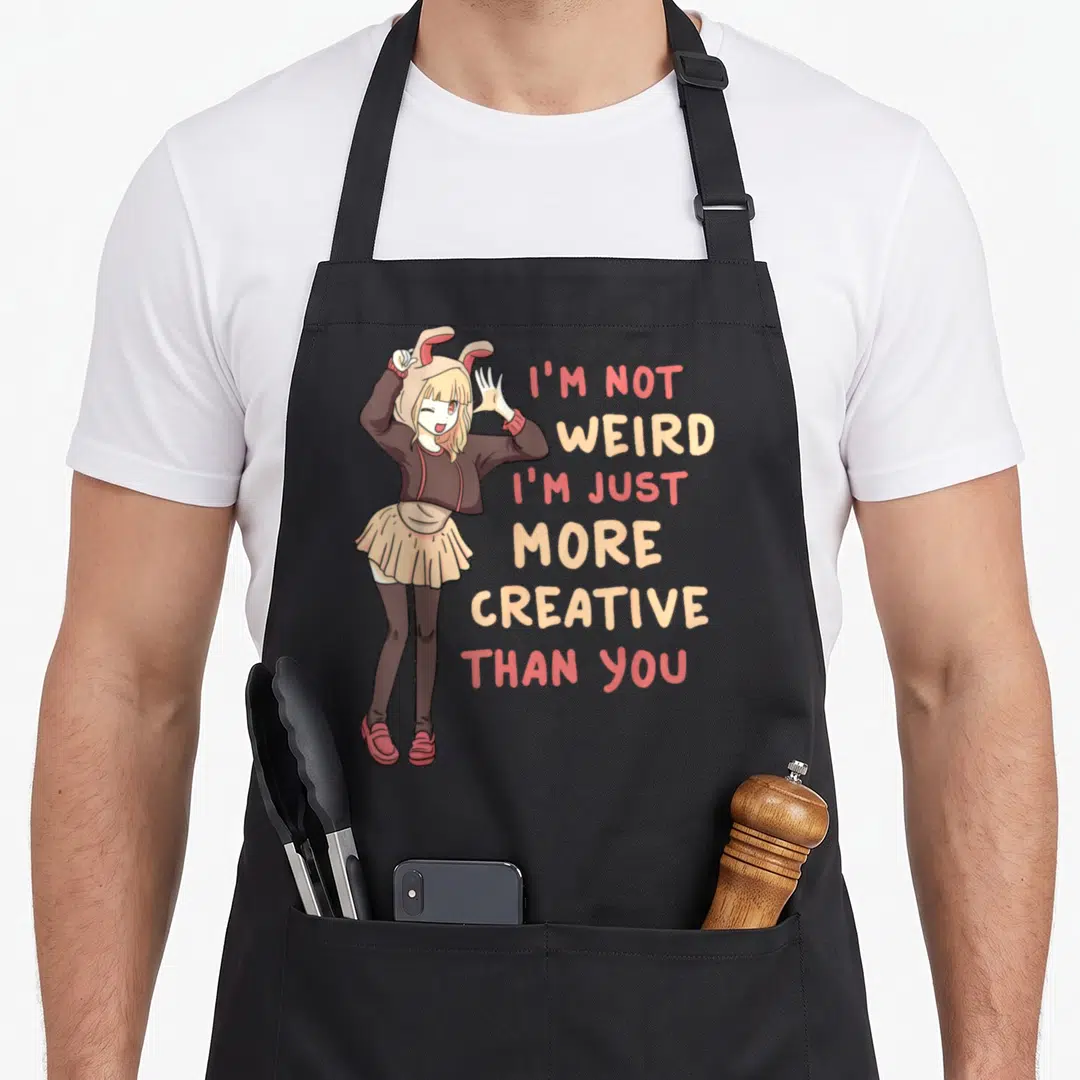 Weird anime apron - Cartoon girl in bunny hat with stacked text I'm not weird I'm just more creative than you — shown on a black cotton canvas apron against a white background
