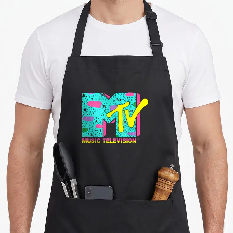 Mtv funky apron - Retro MTV logo with turquoise speckled M, yellow TV script, and MUSIC TELEVISION text below — shown on a black cotton canvas apron against a white background