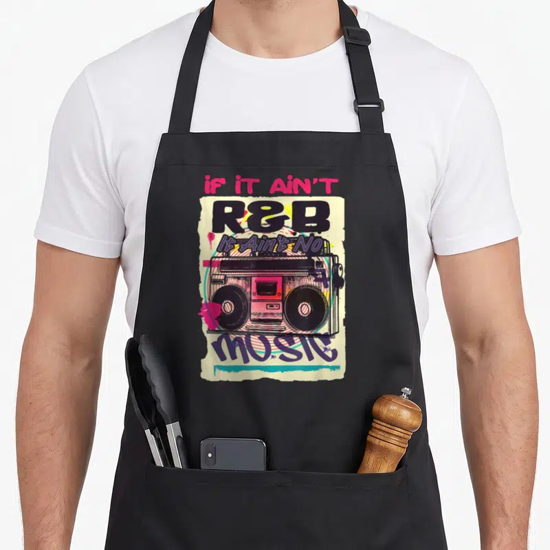 80s r aprons - Retro boombox art with If It Ain't R&B It Ain't No Music text and paint splatters — shown on a black cotton canvas apron against a white background