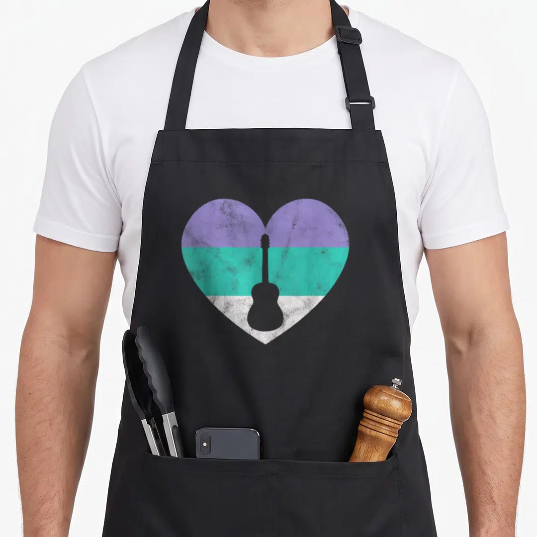 Cute guitar acoustics apron - Heart with purple teal white bands and grey acoustic guitar silhouette — shown on a black cotton canvas apron against a white background