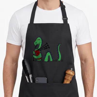 Loch smiletodaytees apron - Green dragon standing playing red plaid bagpipes with black pipes and blue spikes — shown on a black cotton canvas apron against a white background