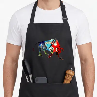 Spain travel aprons - Watercolor bull silhouette containing matador, cathedral, and city buildings in red blue green — shown on a black cotton canvas apron against a white background