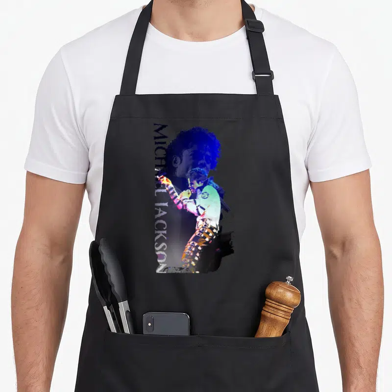 Jackson michaels apron for dad - Distressed blue and purple Michael Jackson holding a mic with vertical name text — shown on a black cotton canvas apron against a white background