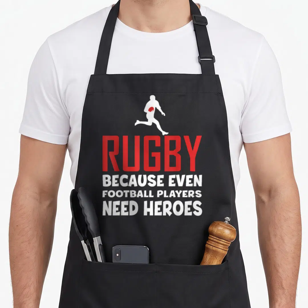 Even football apron - Running rugby player silhouette above bold red RUGBY text and three lines of white slogan text — shown on a black cotton canvas apron against a white background