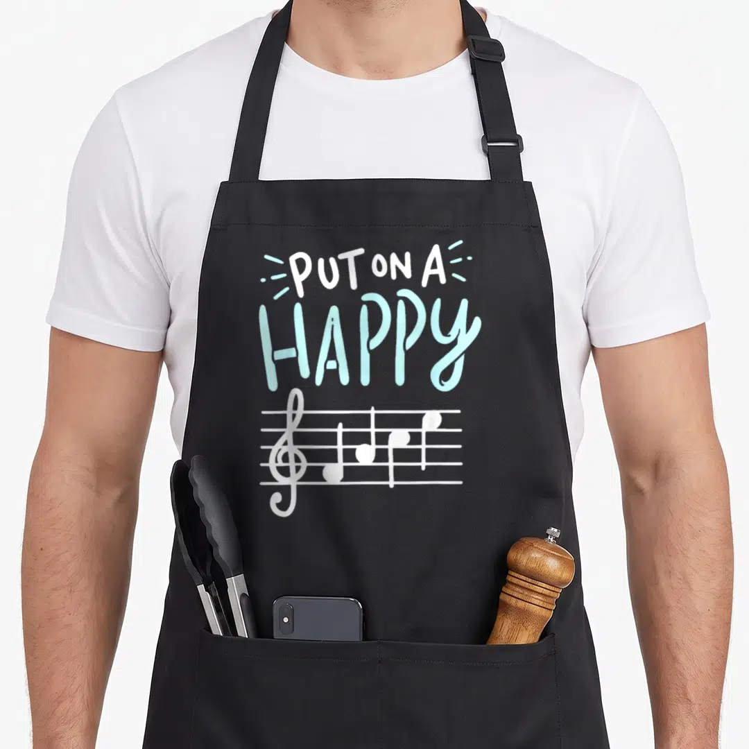 Face music teacher apron - PUT ON A HAPPY text above white musical notes on a staff in light blue — shown on a black cotton canvas apron against a white background