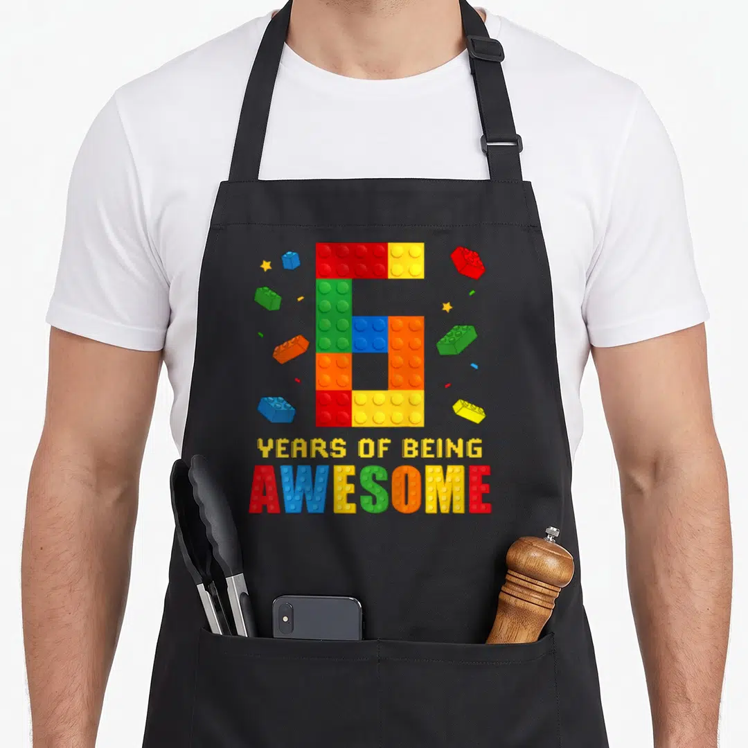 Birthday brick building aprons - Number 6 made of colored blocks with YEARS OF BEING AWESOME text — shown on a black cotton canvas apron against a white background