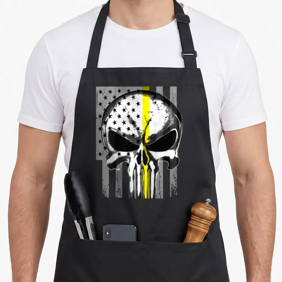 Live tow girl apron - Metallic skull with vertical yellow stripe and scattered black stars on grey background — shown on a black cotton canvas apron against a white background