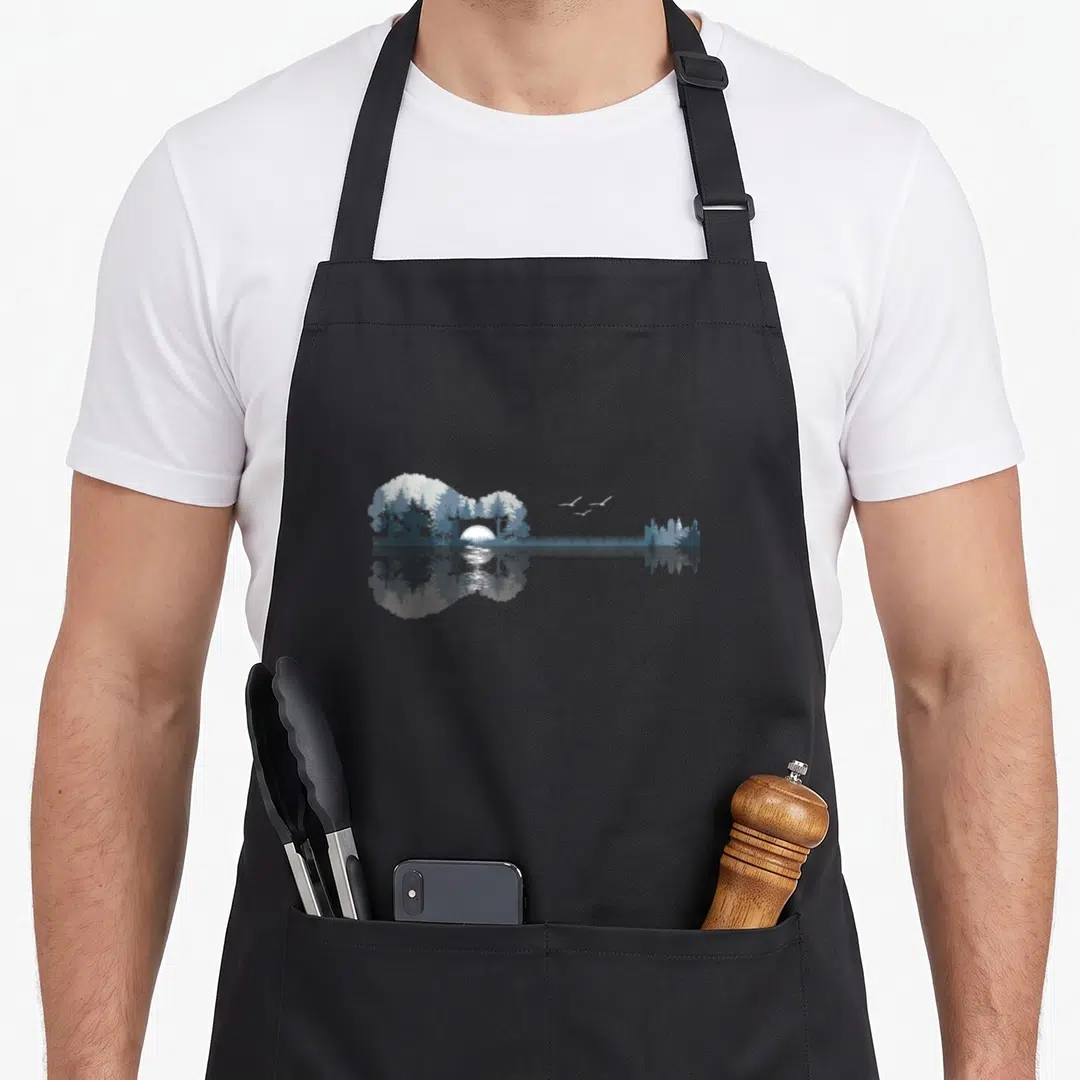Guitar lake acoustics apron - Acoustic guitar silhouette filled with trees, sun, and three birds reflecting in water — shown on a black cotton canvas apron against a white background