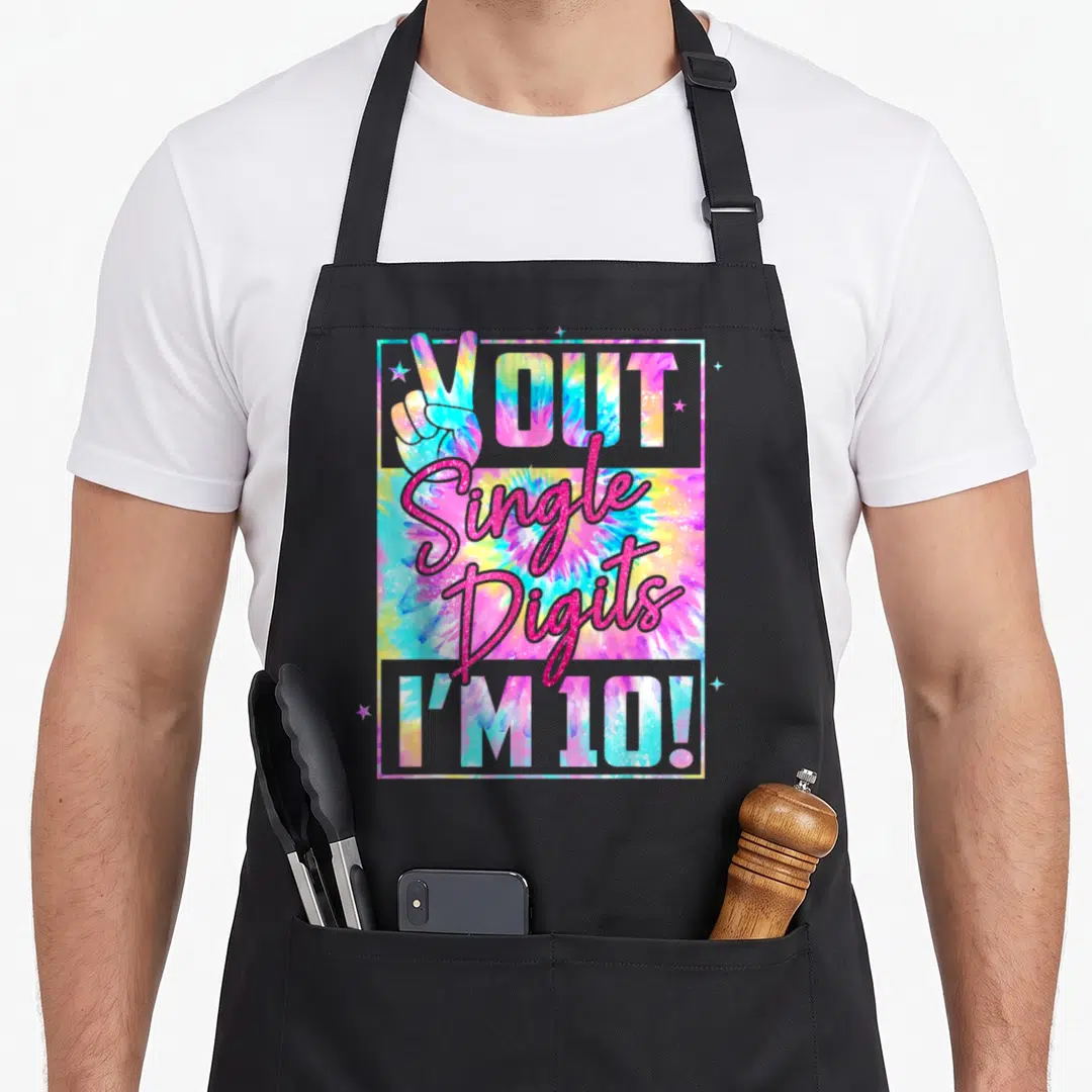 Peace single tie-dye apron - Tie-dye apron with peace sign, pink stars, and glitter text reading OUT Single Digits I'M — shown on a black cotton canvas apron against a white background