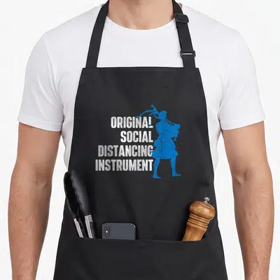 Social pride apron - Original Social Distancing Instrument text beside a blue bagpiper silhouette — shown on a black cotton canvas apron against a white background