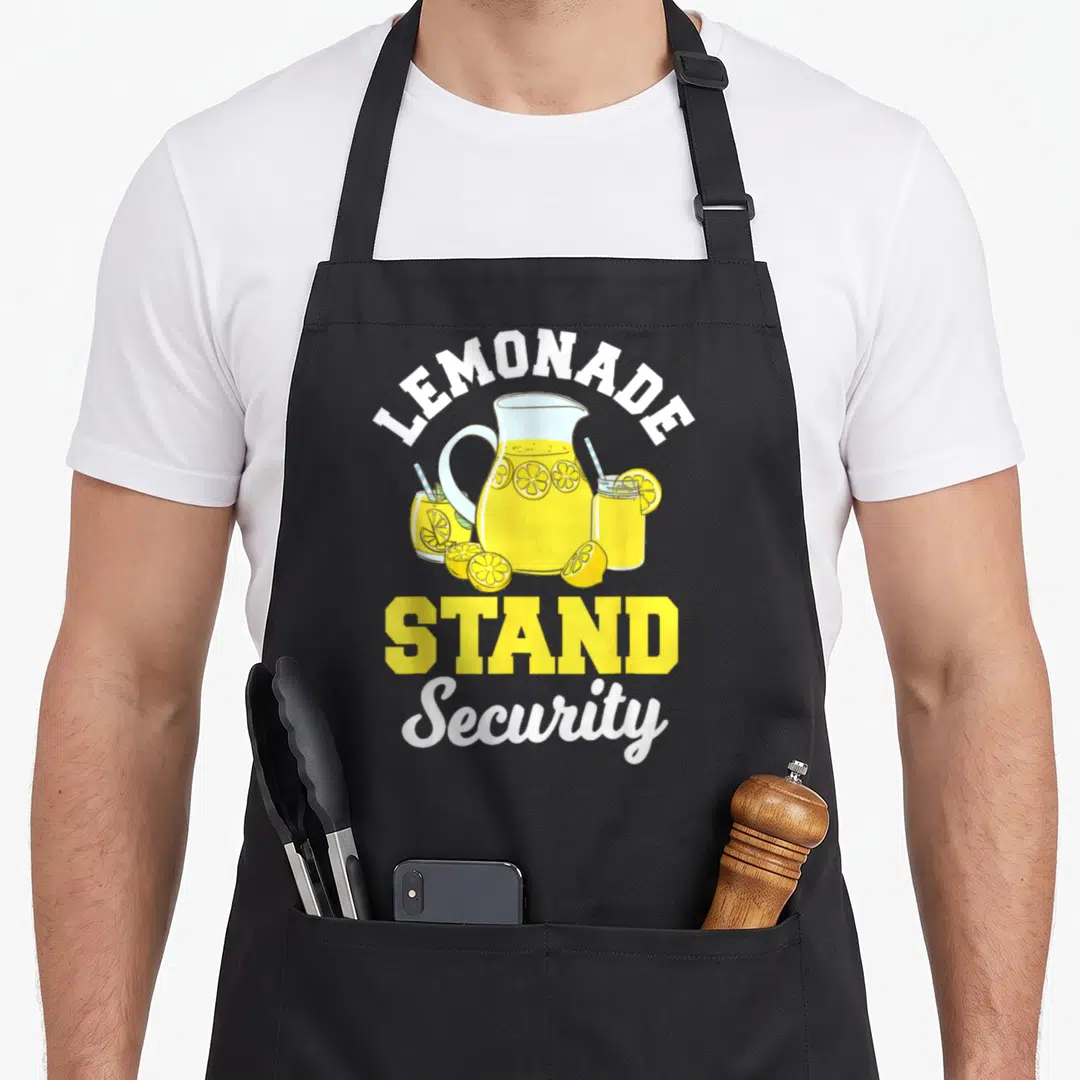 Stand lemon apron - Cartoon pitcher with lemon slices and LEMONADE STAND Security text in yellow white blue — shown on a black cotton canvas apron against a white background
