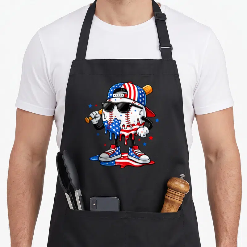 4th drip apron - Cartoon baseball character wearing sunglasses and cap standing in melting flag colors surrounded — shown on a black cotton canvas apron against a white background