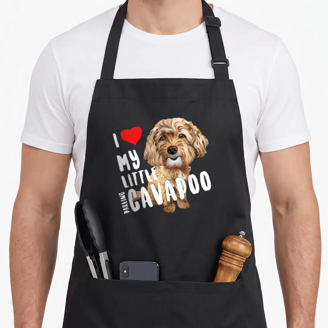 Darling dog apron - Realistic brown and white Cavapoo head with red heart and I love my little darling Cavapoo text — shown on a black cotton canvas apron against a white background