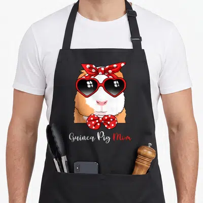 Animal crazy guinea lady apron - Cartoon guinea pig with red heart sunglasses and polka-dot bows, Guinea Pig Mom text — shown on a black cotton canvas apron against a white background