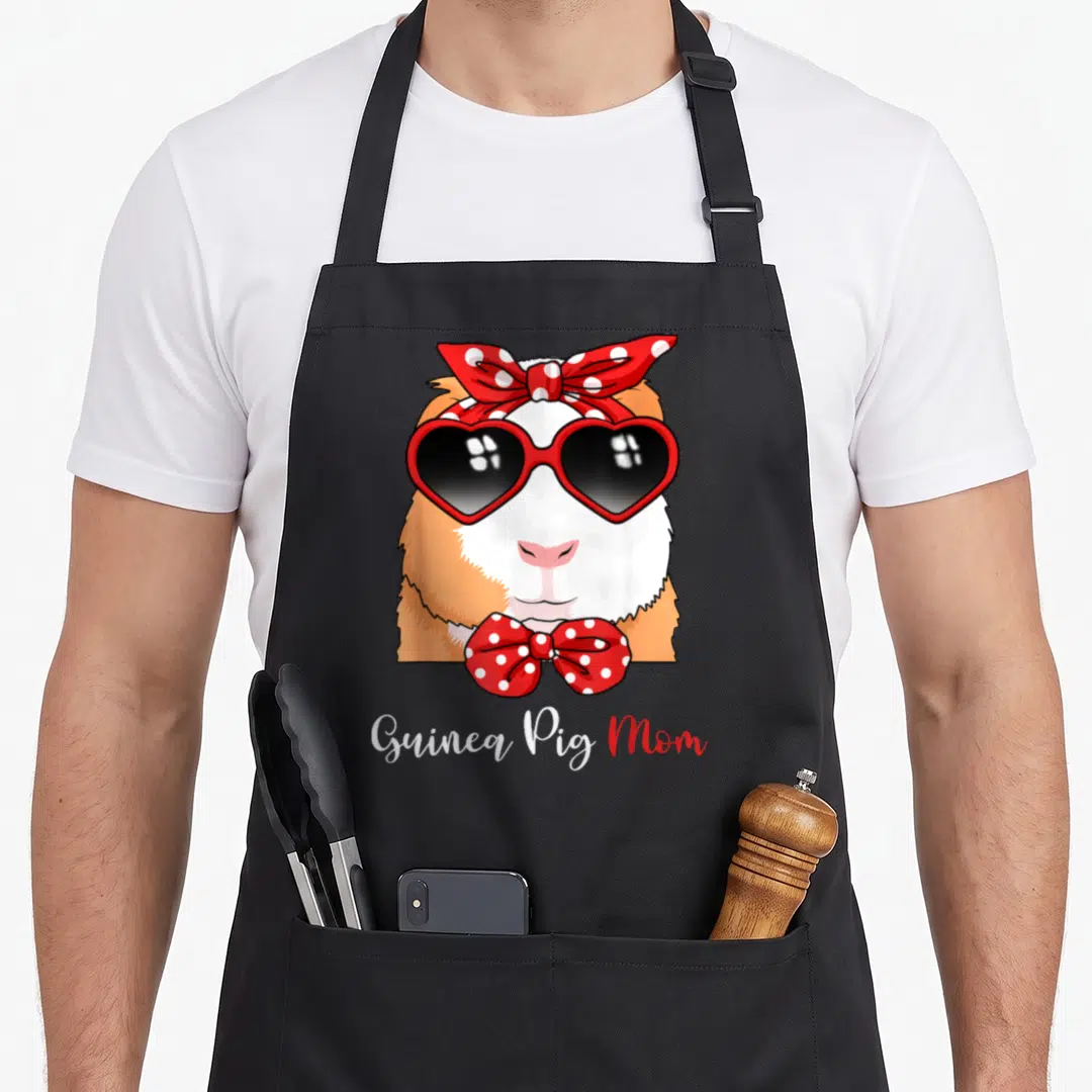 Animal crazy guinea lady apron - Cartoon guinea pig with red heart sunglasses and polka-dot bows, Guinea Pig Mom text — shown on a black cotton canvas apron against a white background