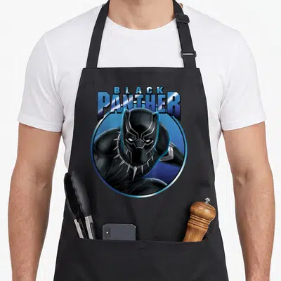 Circle panther apron - Cartoon Black Panther in blue silver circle with bold lettering — shown on a black cotton canvas apron against a white background
