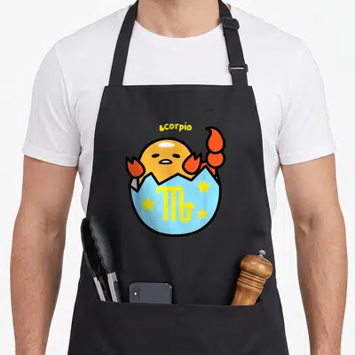 Scorpio gudetama apron - Cartoon scorpion emerging from blue egg shell with three yellow stars and zodiac symbol — shown on a black cotton canvas apron against a white background