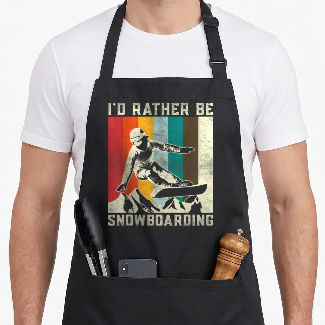 Mountain boarding apron - Retro snowboarder on vertical stripes with I'D RATHER BE SNOWBOARDING text — shown on a black cotton canvas apron against a white background