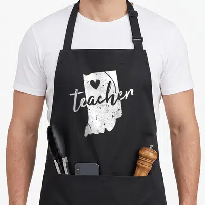 Indiana teacher apron - Distressed white Indiana state map with teacher script and heart icon — shown on a black cotton canvas apron against a white background