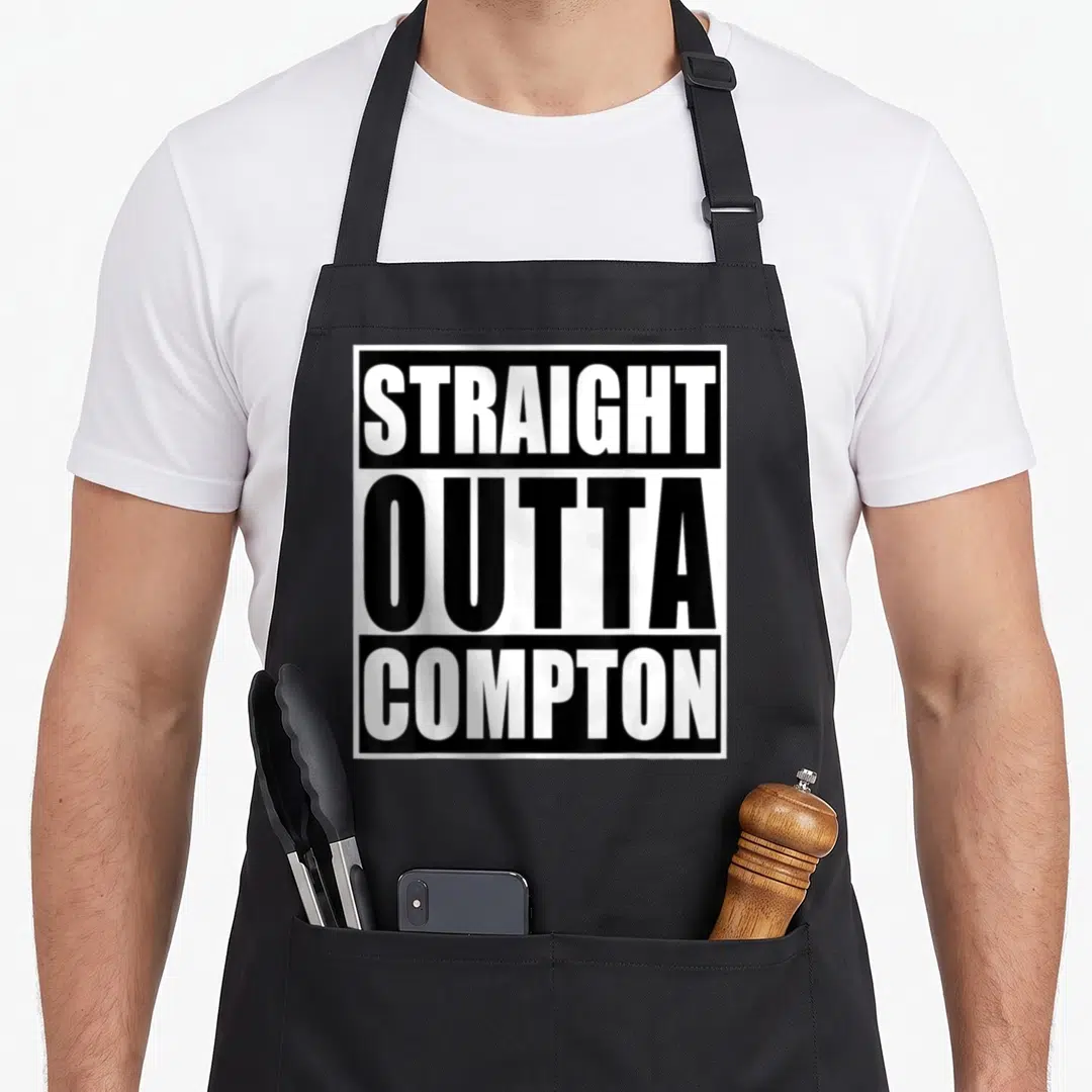 Straight compton apron - Stacked black and white text reading STRAIGHT OUTTA COMPTON inside a square border — shown on a black cotton canvas apron against a white background