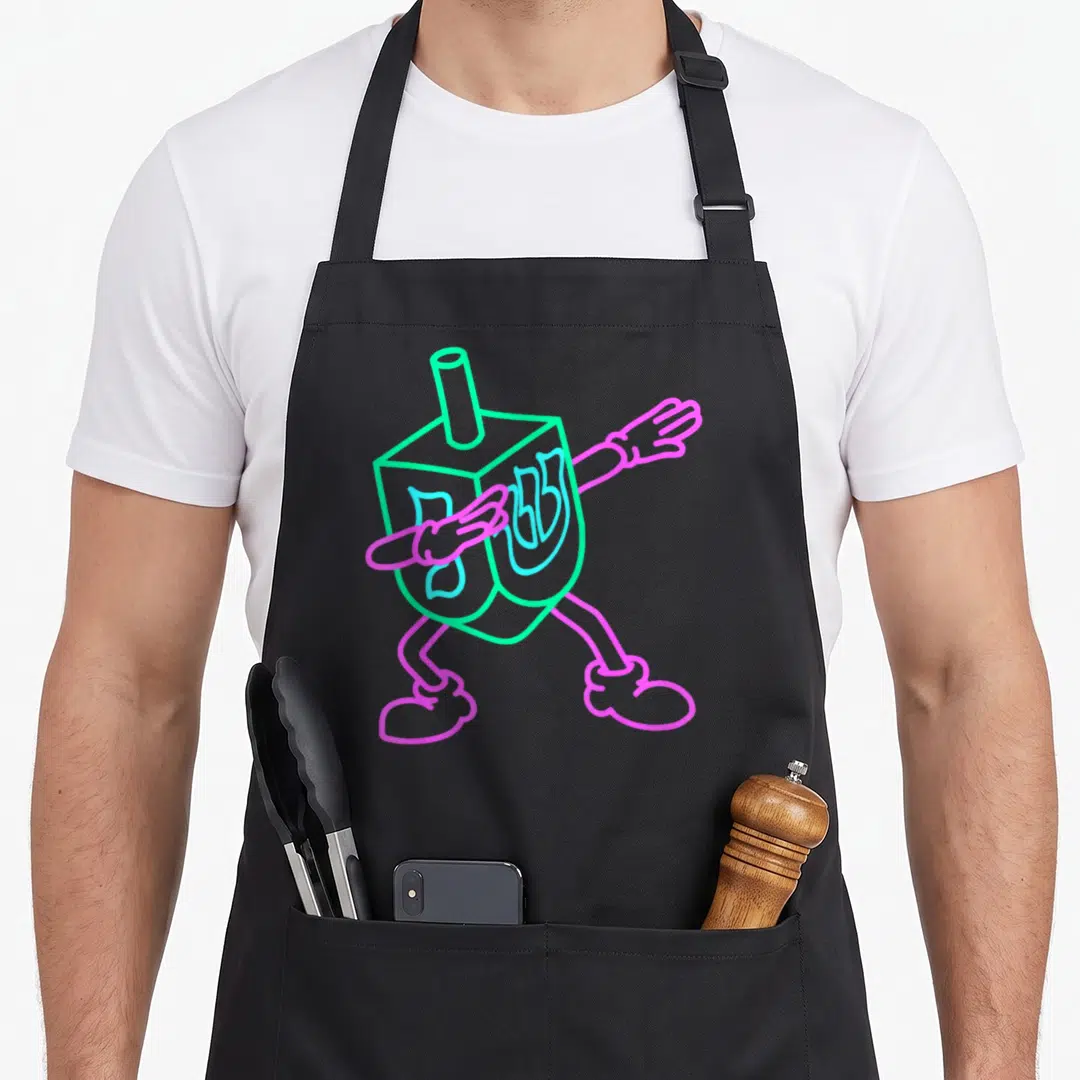 Dabbing hanukkah apron - Neon green dreidel with pink limbs and blue Hebrew letters in a dabbing pose — shown on a black cotton canvas apron against a white background