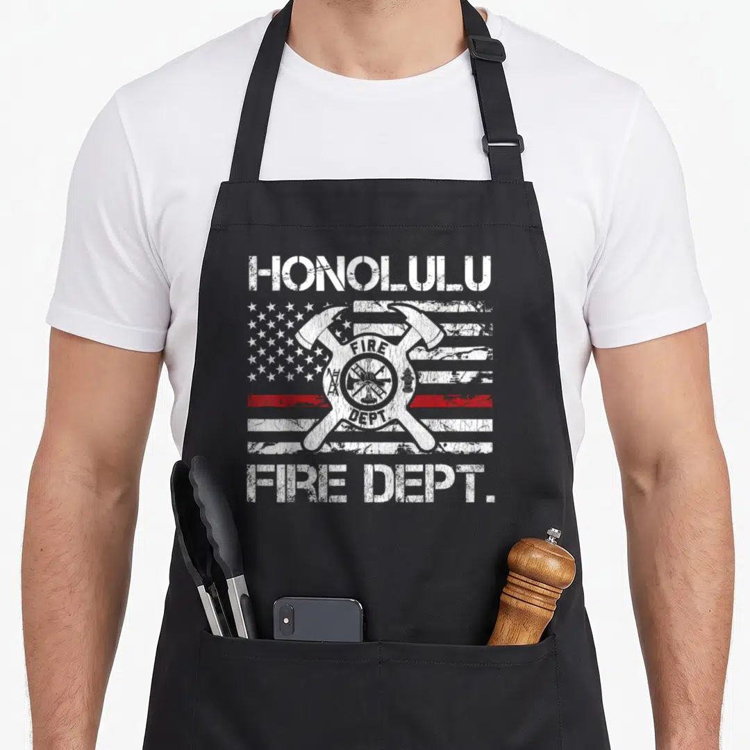 Honolulu fireman apron - Distressed Honolulu Fire Dept text and emblem over flag with red line — shown on a black cotton canvas apron against a white background