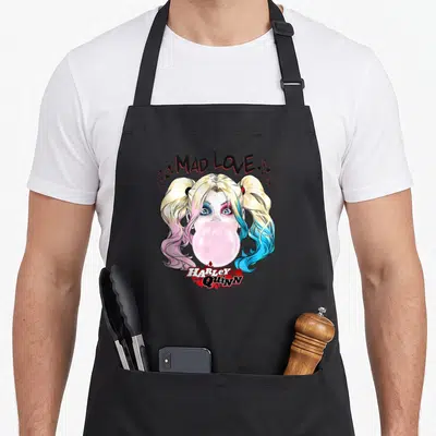 Mad vehicle apron - Cartoon Harley Quinn face blowing pink bubblegum with MAD LOVE text and scattered hearts stars — shown on a black cotton canvas apron against a white background