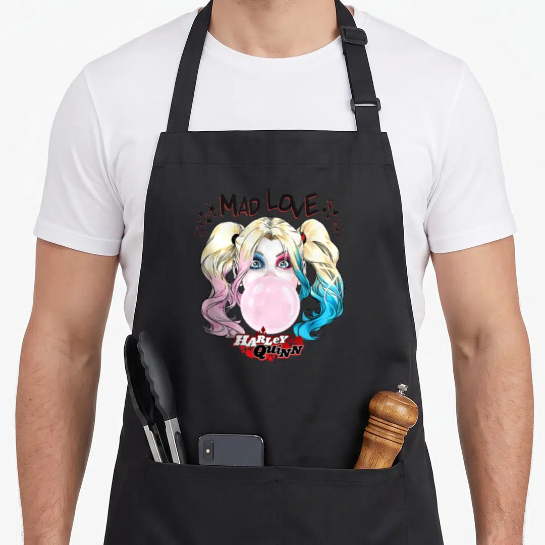Mad vehicle apron - Cartoon Harley Quinn face blowing pink bubblegum with MAD LOVE text and scattered hearts stars — shown on a black cotton canvas apron against a white background