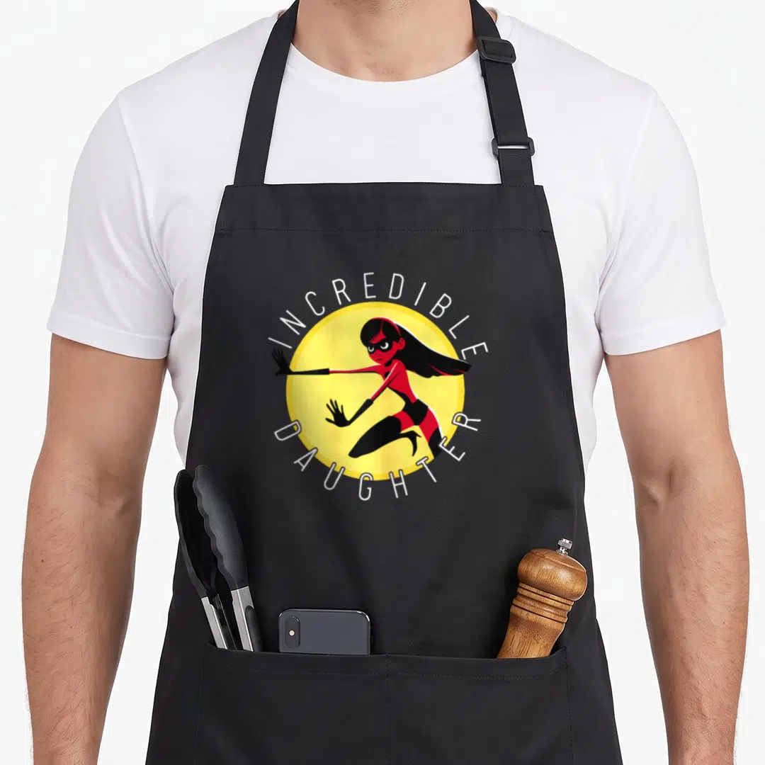 Incredible mom daughter aprons - Superhero girl in red suit inside yellow circle with white text INCREDIBLE DAUGHTER — shown on a black cotton canvas apron against a white background