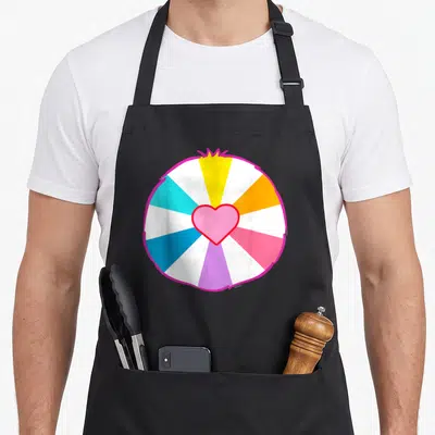 Hopeful halloween apron - Pink heart inside circle of cyan, orange, purple, blue, yellow, white, and pink wedges — shown on a black cotton canvas apron against a white background
