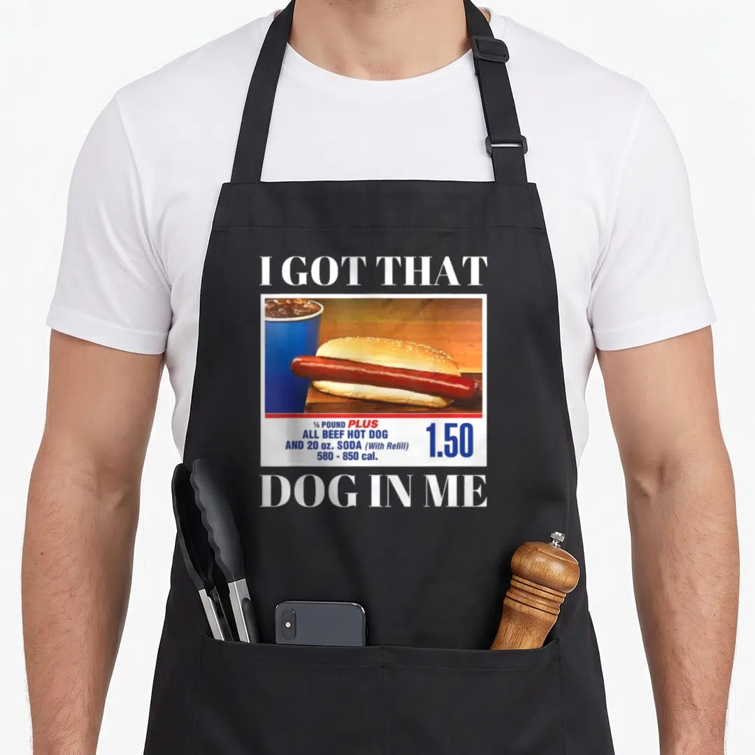 Meme dog apron - Retro hot dog and soda ad with I GOT THAT DOG IN ME text and 1.50 price tag — shown on a black cotton canvas apron against a white background