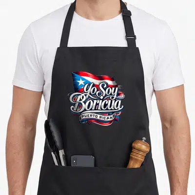 Boricua soy apron - Yo Soy Boricua script over red white blue Puerto Rico flag with PUERTO RICAN ribbon banner — shown on a black cotton canvas apron against a white background