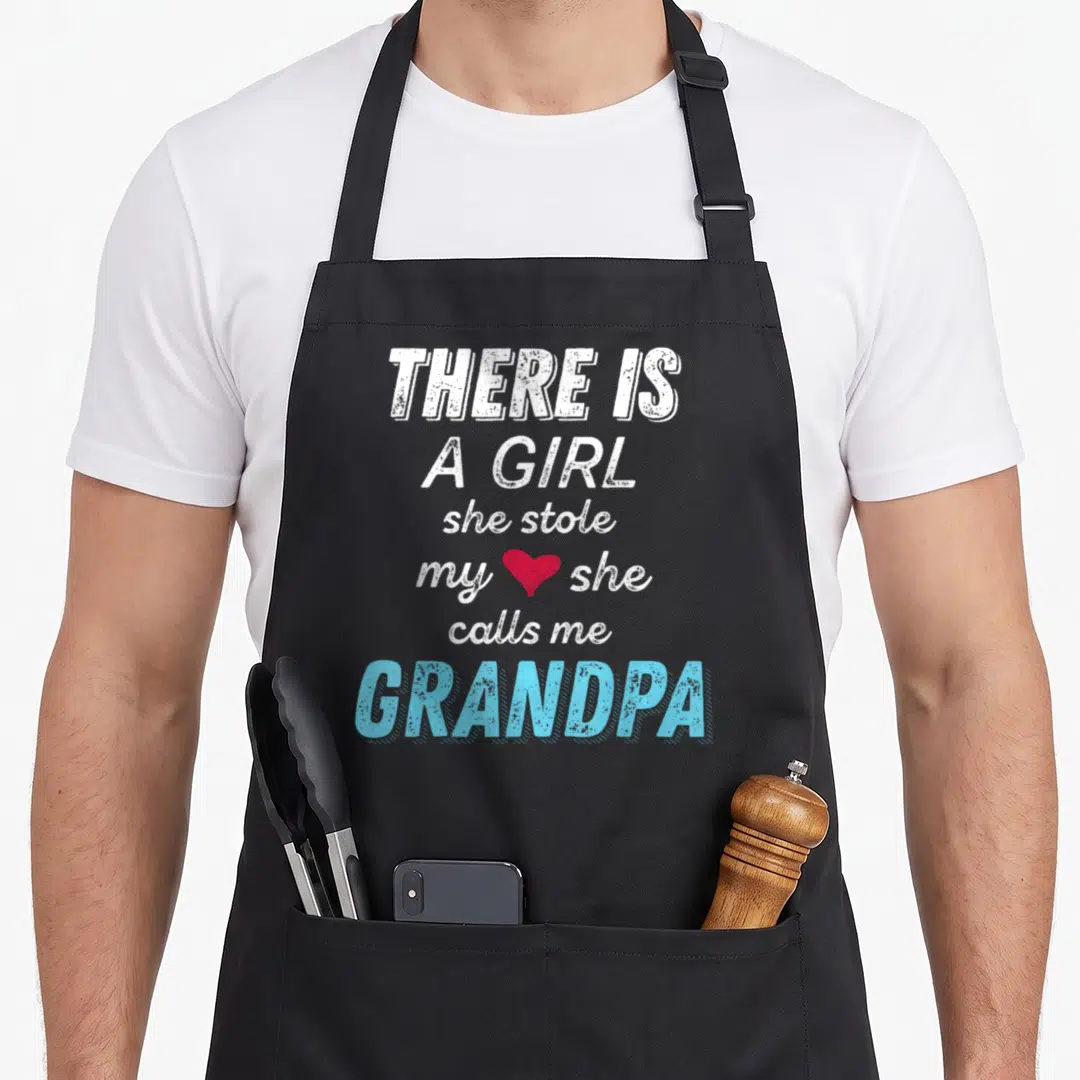 Grandpa granddaughter father day apron - Stacked text reading there is a girl she stole my heart she calls me grandpa — shown on a black cotton canvas apron against a white background