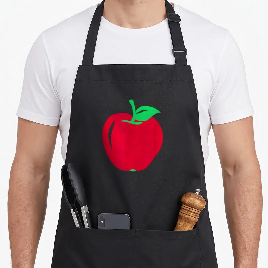 Funny apple apron - Minimalist red apple graphic with green leaf and stem on canvas — shown on a black cotton canvas apron against a white background
