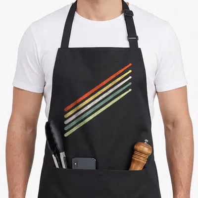 Drummer pigeon vintage apron - Five diagonal drumsticks in red yellow white green and light green with distressed — shown on a black cotton canvas apron against a white background