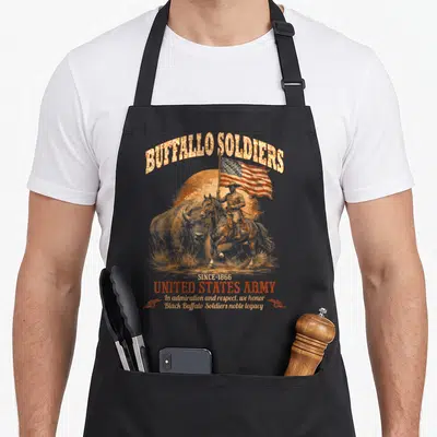 Buffalo military apron - Soldier on horseback holding flag with bison and cannons in distressed gold and red — shown on a black cotton canvas apron against a white background